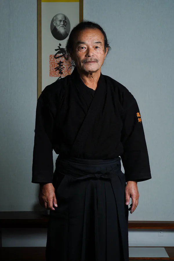 開祖の肖像を掲げた掛軸の前に立つ高安三郎先生。